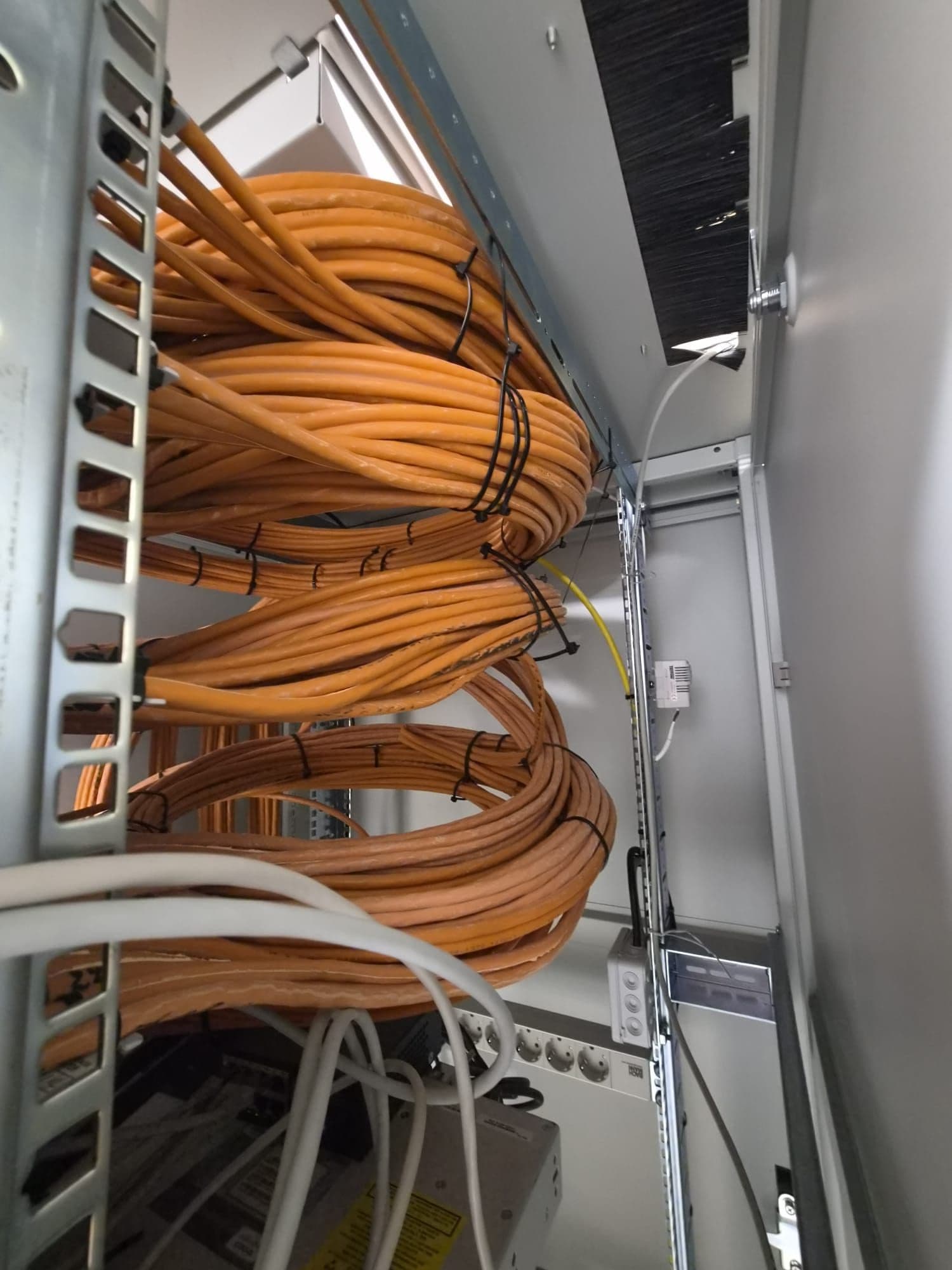 Orangefarbene Netzwerkkabel ordentlich in einem Technikschrank